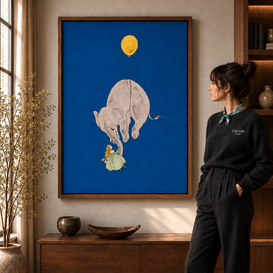 Whimsical elephant canvas wall art in a walnut frame beside a woman in black and a wooden cabinet.