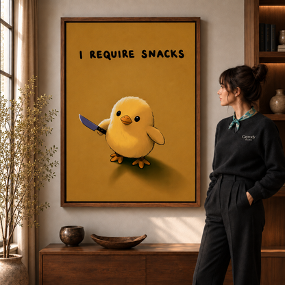 Woman beside walnut-framed funny chick wall art with the words “I REQUIRE SNACKS.”